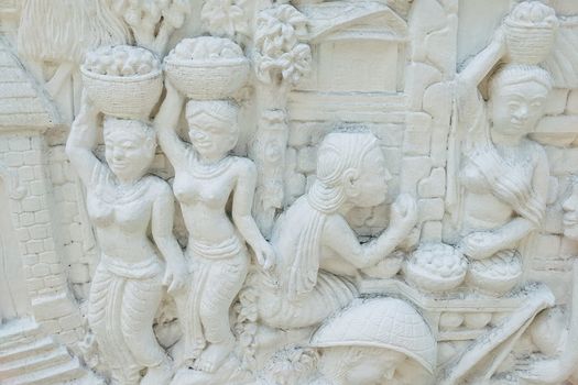 Detailed ancient bas relief sculpture depicting traditional life scenes in finely carved stucco artwork.