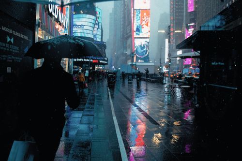 Free Pedestrians walking under umbrellas on a rainy night in Times Square, NYC. Stock Photo