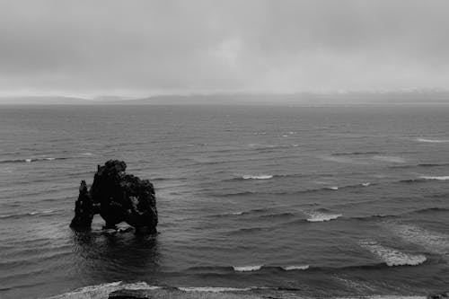 Grayscale Photo of a Rock Formation on the Sea