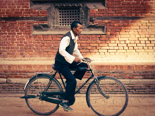 Man Riding a Bicycle near a Brick Wall