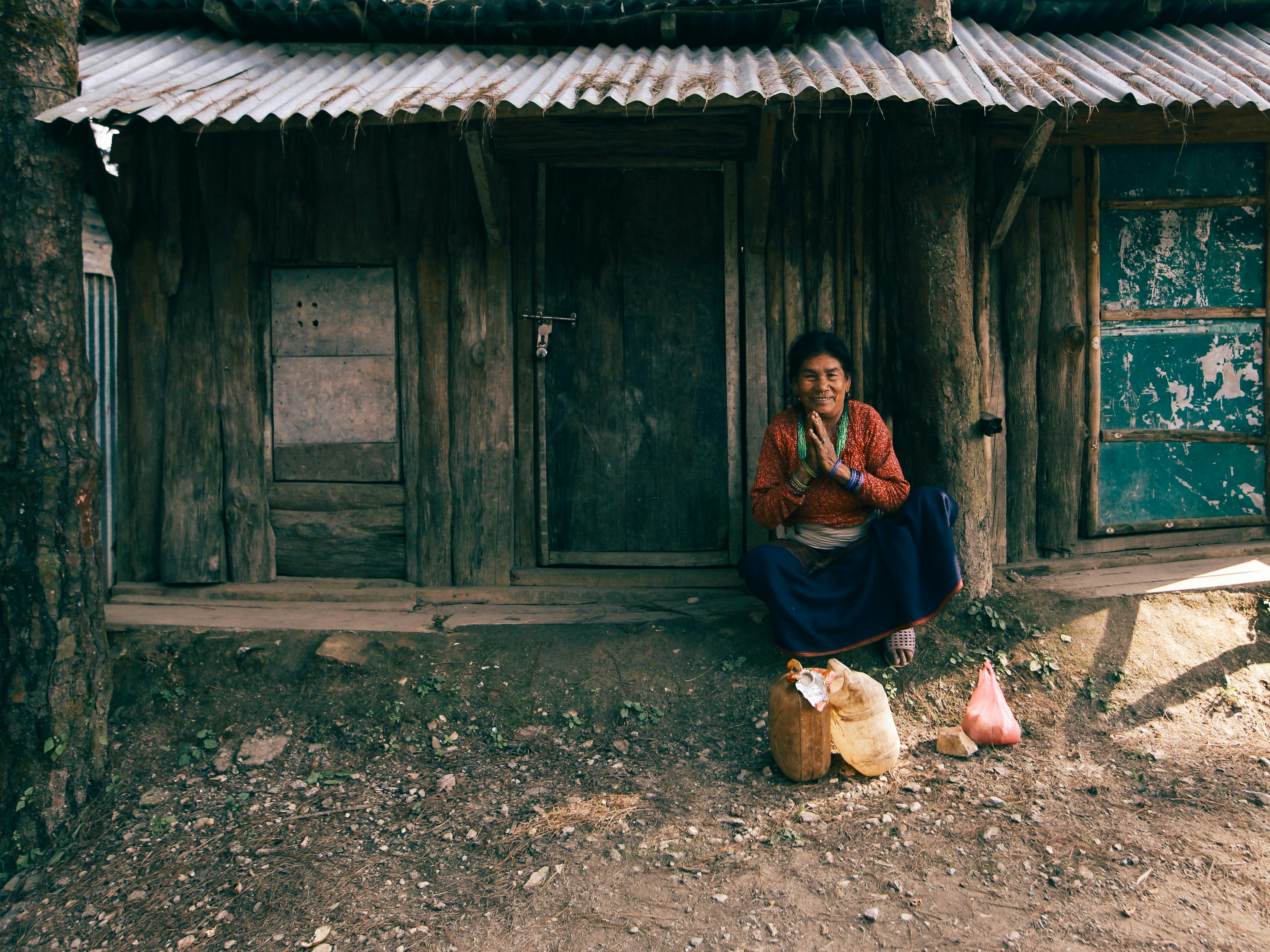 A woman sits at the entrance of a rustic cabin, offering a serene countryside vibe.