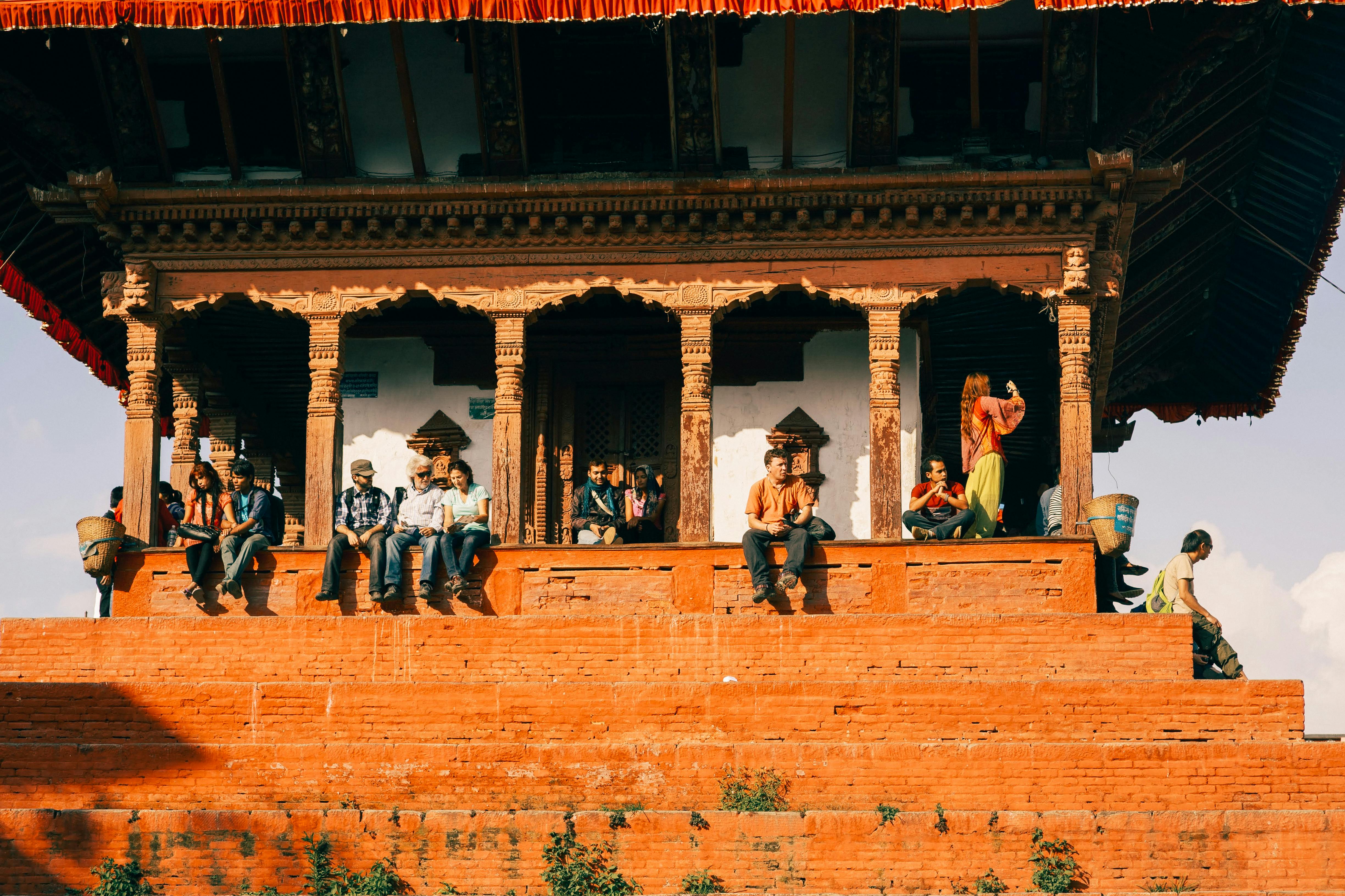 Kathmandu Durbar Square at dusk with pagoda temples lit by oil lamps and devotees walking below