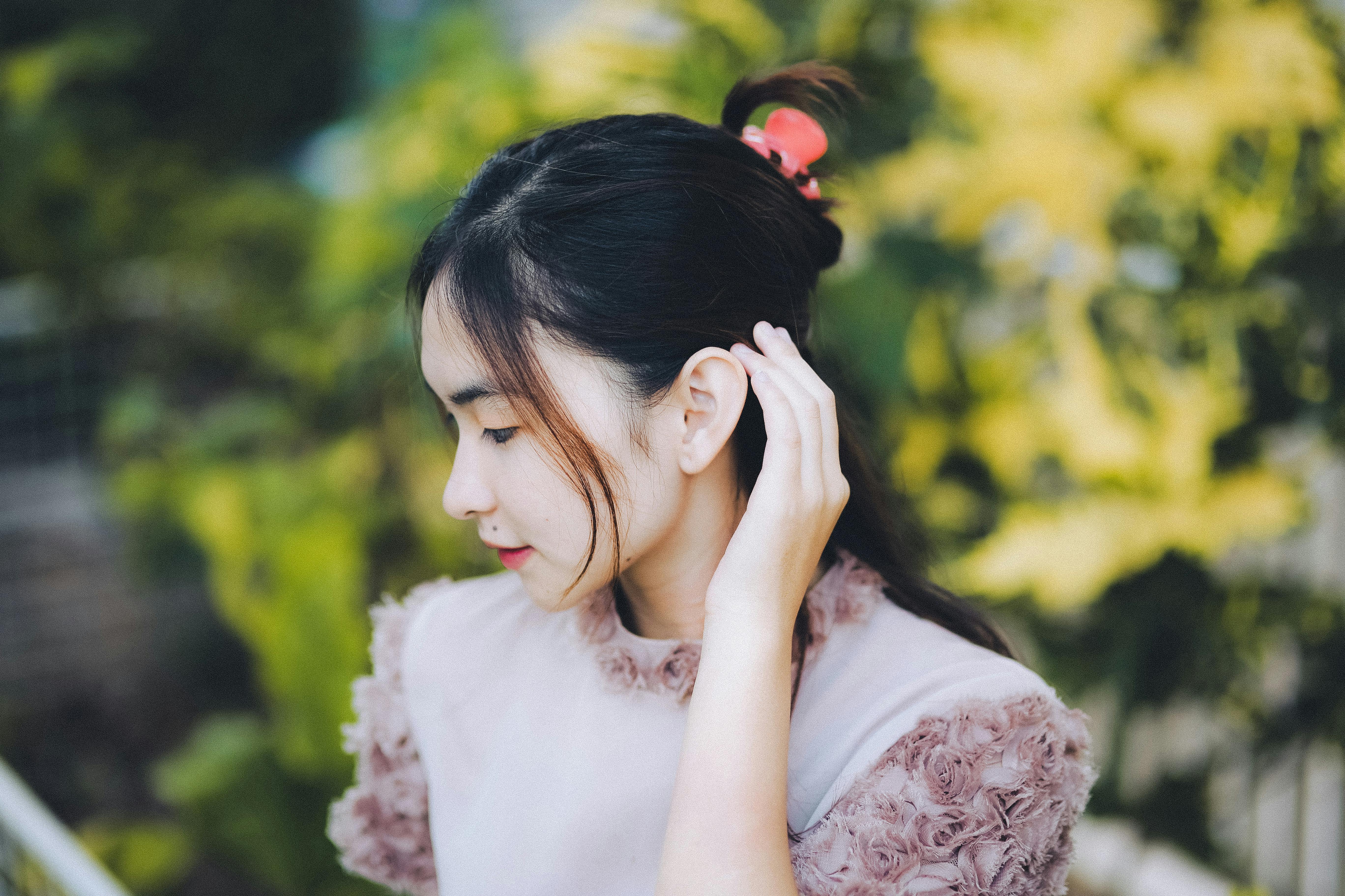 Side profile of a young Indonesian woman in natural light, captured with soft focus.