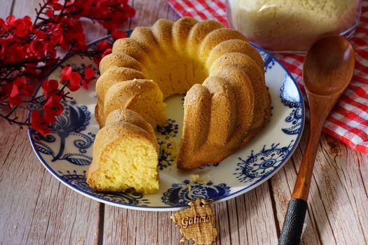 Intricate homemade bundt cake beautifully presented with red flowers on a wooden background.