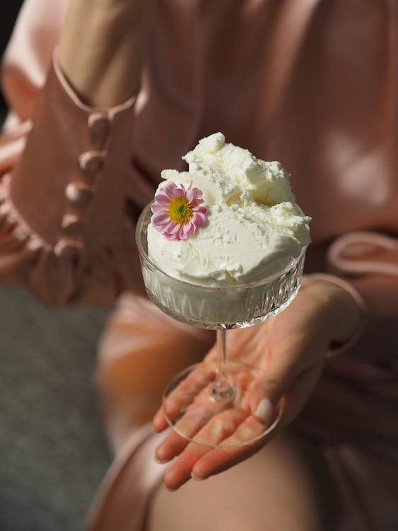 Selective Focus of a Person Holding a White Ice Cream in Coupe Glass