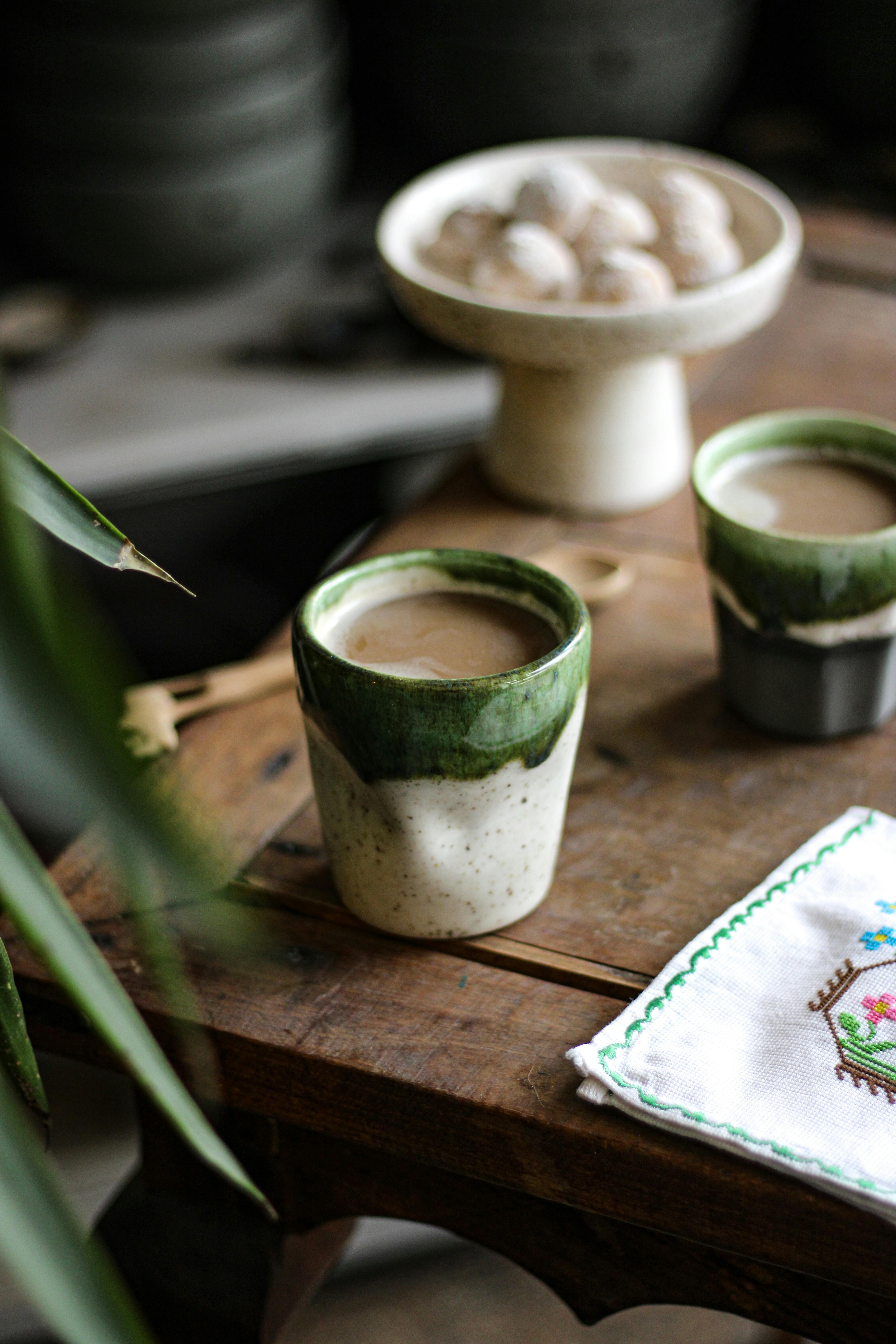 Artisan ceramic cups filled with coffee on a rustic wooden table, perfect for a relaxing moment.