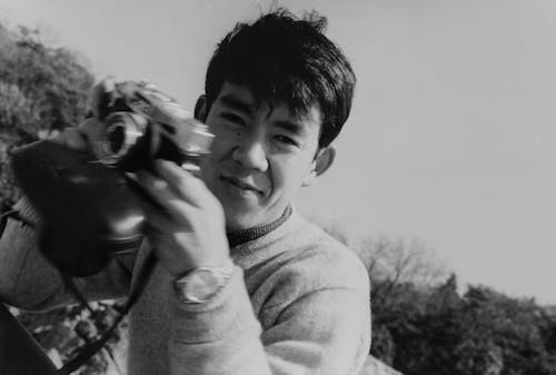 Grayscale Photo of a Woman holding Camera 