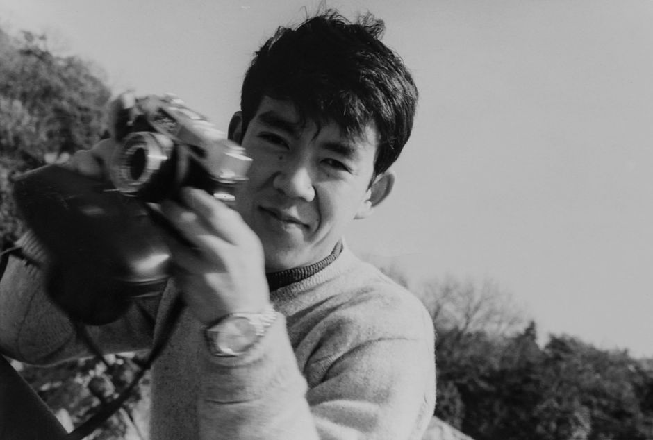 Black and white outdoor portrait of a male photographer holding a classic camera in Japan.