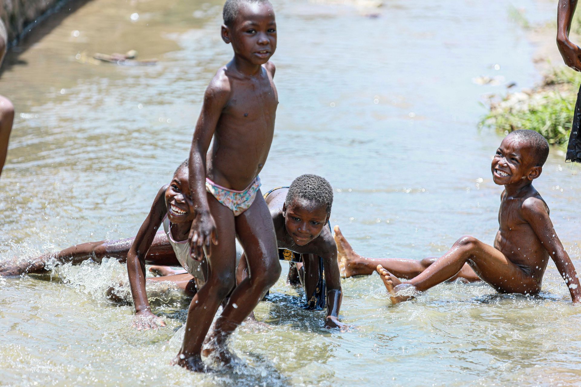 Happy children enjoying and playing in a sunny stream, splashing water and having fun outdoors.