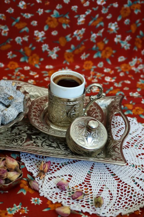 Free A beautiful silver Turkish coffee set with sweets on a floral backdrop, perfect for cultural themes. Stock Photo