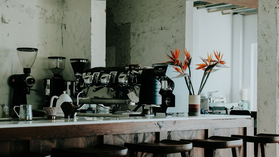 Stylish café interior featuring espresso machine, grinders, and floral decor on a sleek counter.