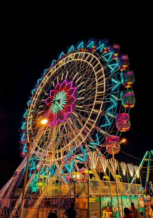 Free Colorful illuminated Ferris wheel at a night carnival in Bengaluru, India, showcasing vibrant lights and festive atmosphere. Stock Photo