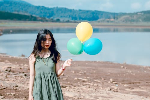 Mulher Com Vestido Verde Sem Mangas Segurando Três Balões