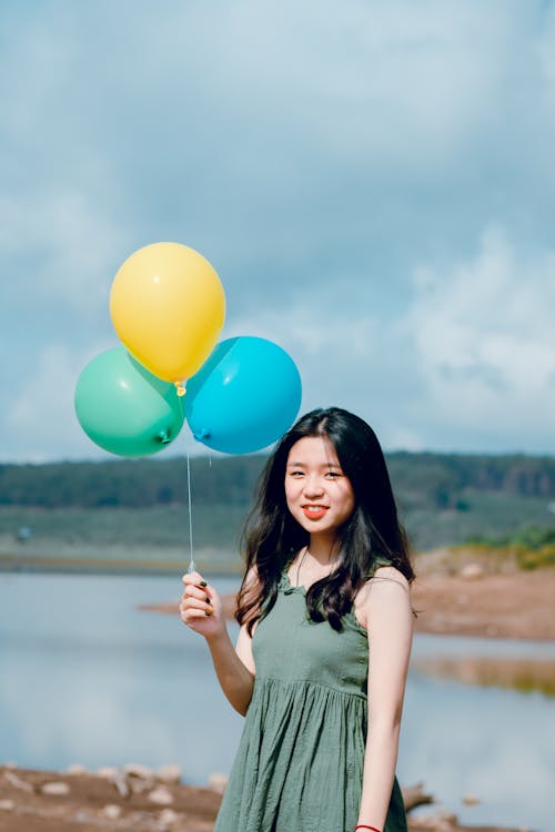 Femme Vêtue D'une Robe Verte Tenant Des Ballons Près De La Rivière