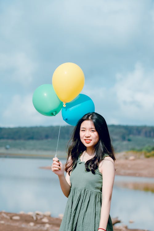 Mulher Com Blusa Sem Mangas Verde Segurando Balões