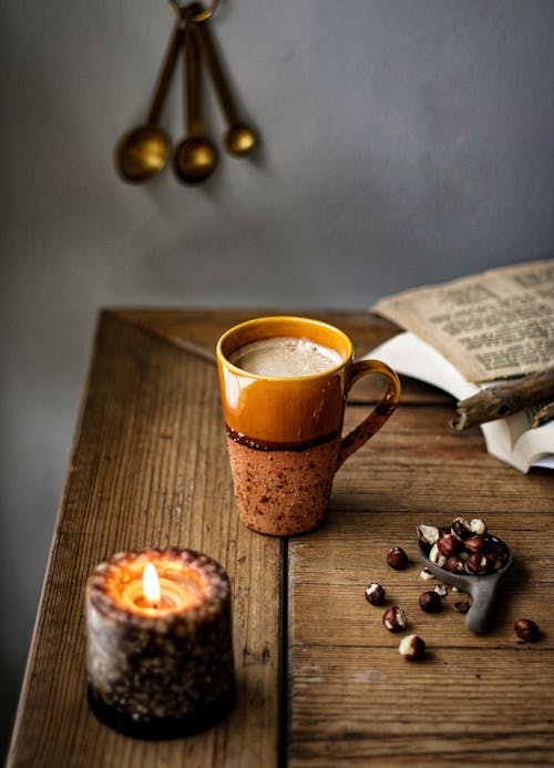 Coffee in Ceramic Cup and Lit Candle on Wooden Table 