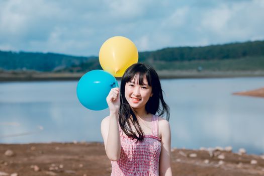一位年轻女子在宁静的湖边拿着气球