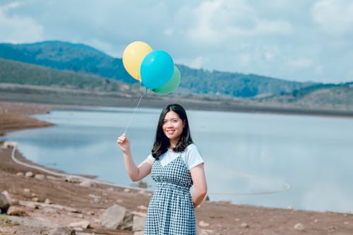 Женщина на берегу моря, держа воздушные шары