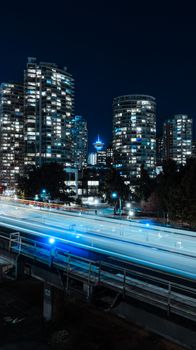 Illuminated Vancouver skyline at night featuring light trails and skyscrapers.