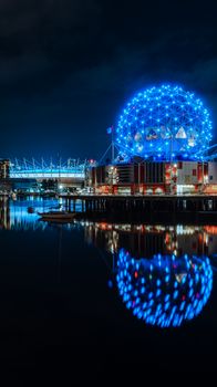 Captivating night view of illuminated Science World reflecting over Vancouver's tranquil river.