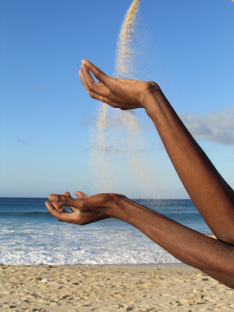 Person Hands Throwing Sand On Beach