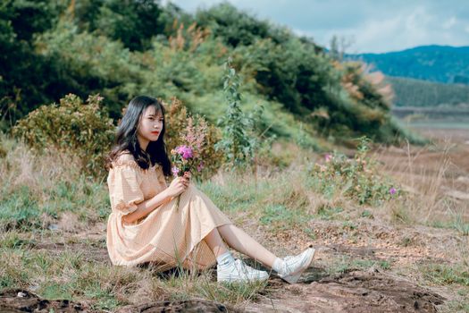 一位年轻女子身穿花卉连衣裙，坐在郁郁葱葱的绿叶中，享受大自然的宁静时刻