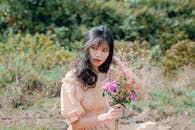 一位穿着夏装的亚洲妇女，在郁郁葱葱的田野里捧着鲜花