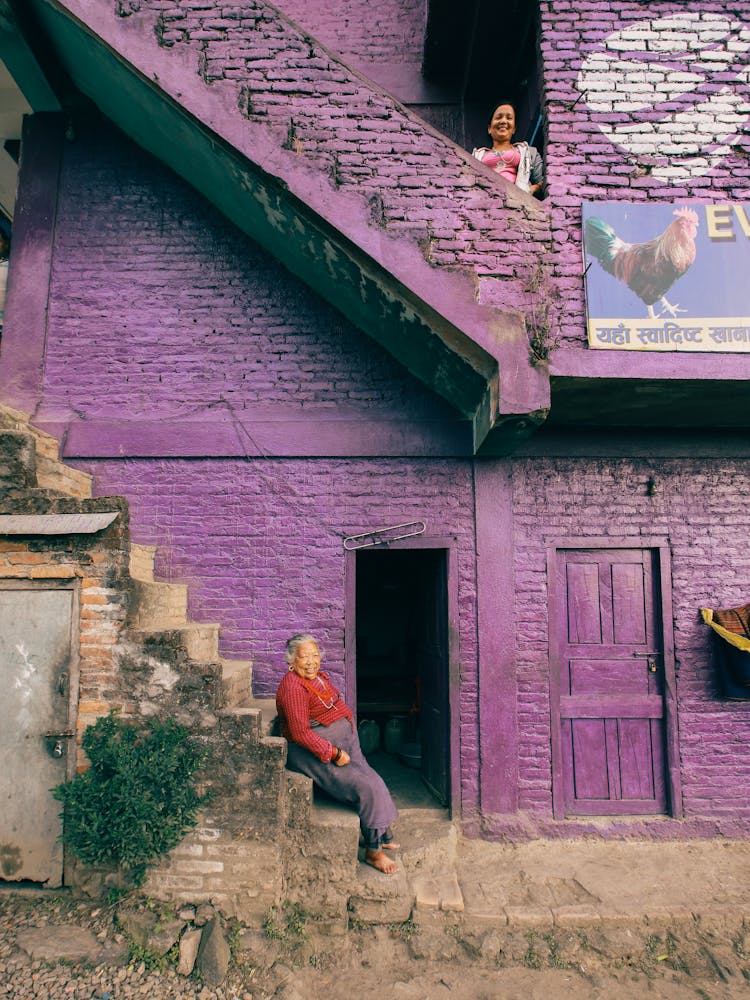 Cheerful Senior Women Looking From Stairs Of Violet Slum House