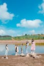 一群年轻的亚洲女性在湖边享受着阳光明媚的一天，头顶是充满活力的蓝天