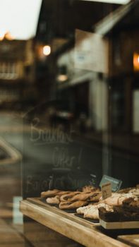A cozy bakery window showcasing an assortment of fresh pastries on a wooden tray.