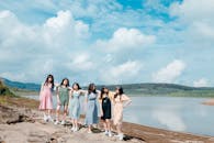 六个朋友在湖边一起站着，享受晴朗的日子、蓝天和云彩