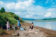 在一个阳光明媚的日子里，一群年轻女子在宁静的湖边放松身心，捕捉大自然的美丽