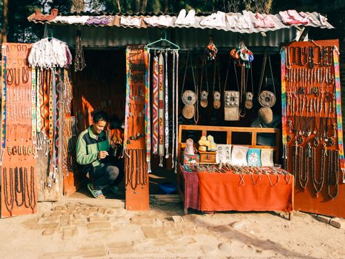 Free A vibrant street market stall selling traditional jewelry with a smiling vendor. Stock Photo