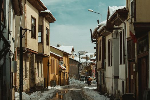 A snow-covered street lined with quaint buildings in a charming village during winter.