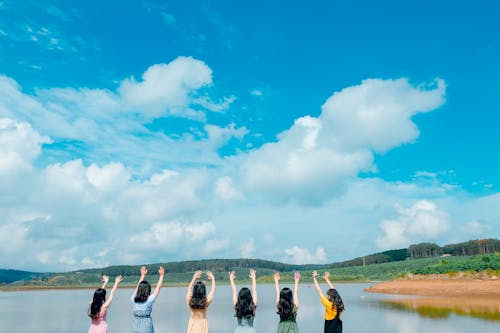 Free Group of Women Wearing Dress Raising Up Their Hands on Air Under Cloudy Sky Stock Photo