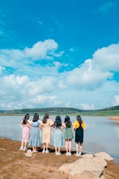 在明亮的蓝天下，六个年轻女子欣赏着湖光山色，象征着友谊