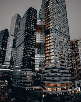 Photo of modern skyscrapers illuminated at dusk, showcasing urban architectural design and high-rise structures.