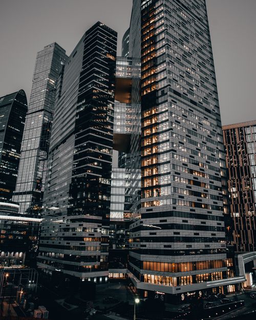Free Photo of modern skyscrapers illuminated at dusk, showcasing urban architectural design and high-rise structures. Stock Photo