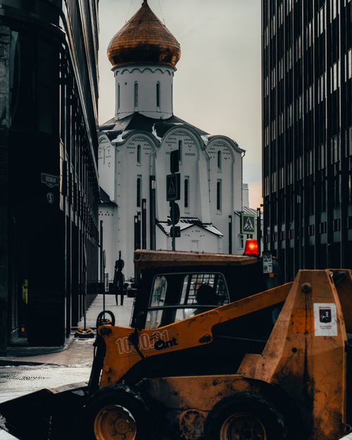Free A city street with a church and bulldozer, blending urban and historical elements. Stock Photo