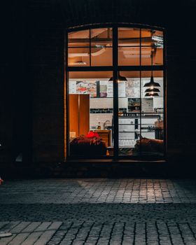 Warmly lit café interior viewed from street at night, showcasing a serene and inviting ambiance.