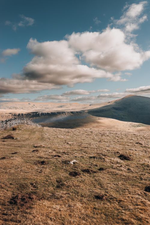 Free Breathtaking view of a vast mountainous landscape under a sky filled with fluffy clouds. Stock Photo