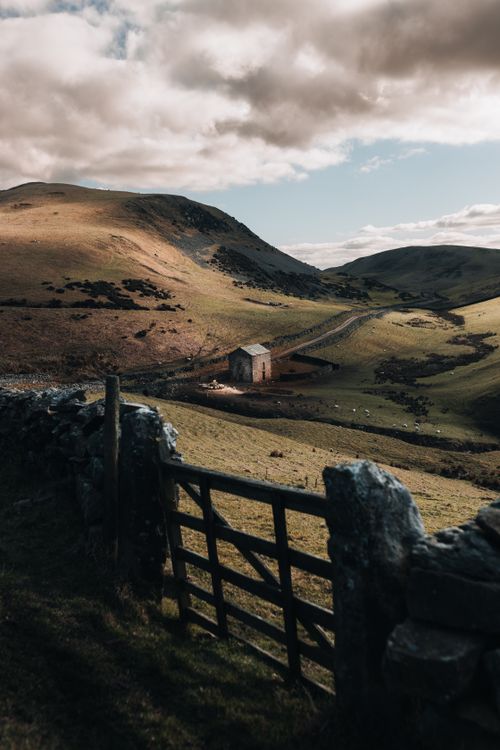 Free Breathtaking rustic landscape capturing rolling hills and a lone house at dawn. Stock Photo