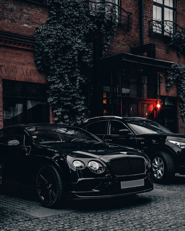Black Vehicle Parked Beside a Brick Building · Free Stock Photo