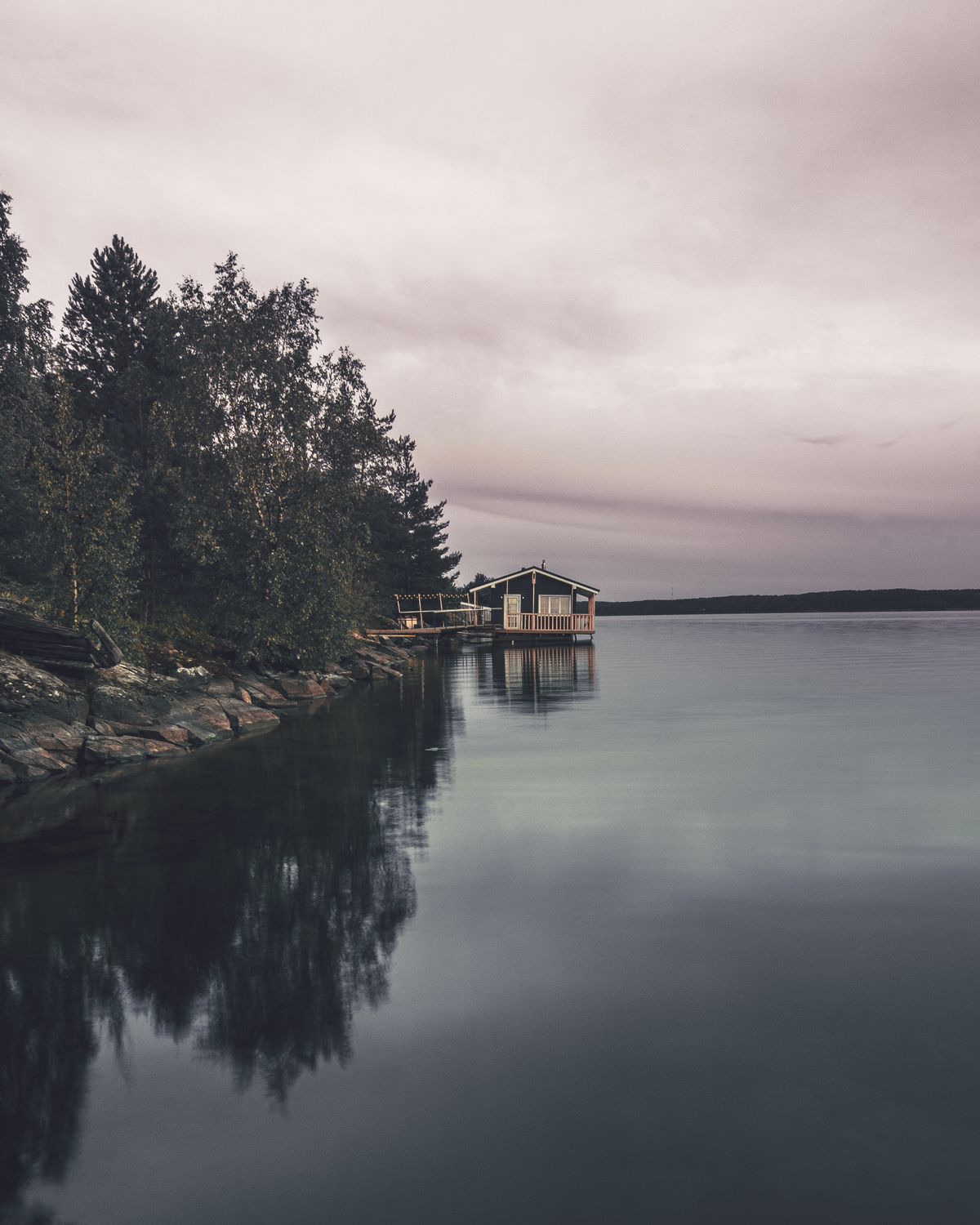 Cabin on a quiet northern lake shoreline at dusk