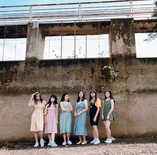 Группа женщин, стоящих у коричневой стены