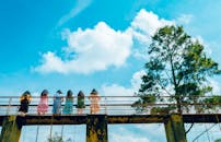 一群妇女穿着彩色连衣裙，站在桥上，映衬着充满活力的蓝天