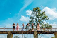一群年轻女性在乡村桥上摆姿势，背景是充满活力的蓝天和绿树
