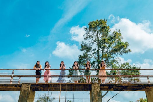 一群年轻女性在乡村桥上摆姿势，背景是充满活力的蓝天和绿树