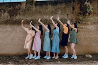 一群年轻女子在乡村墙边嬉笑起舞，户外洋溢着她们的喜悦与友谊