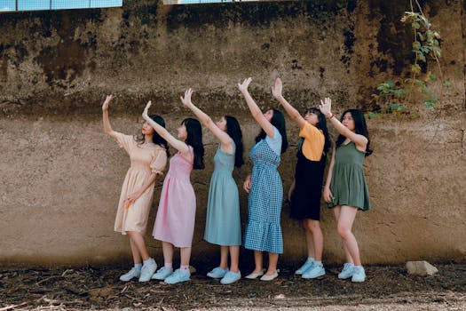 一群年轻女子在乡村墙边嬉笑起舞，户外洋溢着她们的喜悦与友谊